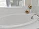 Oval soaking tub with white tile and modern fixtures at 2725 Leafwing Ct, Palm Harbor, FL 34683