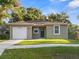 Newly constructed home with a green exterior, white garage door, and landscaped lawn at 6904 E 18Th Ave, Tampa, FL 33619