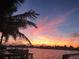 Picturesque waterfront sunset view featuring a boat docked by a charming palm tree at 16343 Redington Dr, Redington Beach, FL 33708