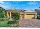 Inviting yellow house with landscaped lawn, paved driveway, and two-car garage at 721 Manns Harbor Dr, Apollo Beach, FL 33572