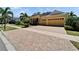 Attractive yellow home with a two-car garage, brick paver driveway and manicured lawn at 721 Manns Harbor Dr, Apollo Beach, FL 33572