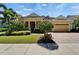Lovely yellow home featuring tropical landscaping, brick driveway, and inviting curb appeal at 721 Manns Harbor Dr, Apollo Beach, FL 33572