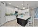 Bright kitchen with white cabinets, a dark island, stainless appliances, and a tile backsplash at 721 Manns Harbor Dr, Apollo Beach, FL 33572
