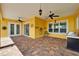 Large covered lanai featuring brick pavers, ceiling fan, grill and bright yellow walls at 721 Manns Harbor Dr, Apollo Beach, FL 33572