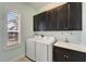 Bright laundry room with a sink, washer and dryer and dark cabinets at 721 Manns Harbor Dr, Apollo Beach, FL 33572