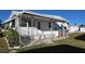 Side view of a white mobile home with covered patio and AC unit at 2331 Belleair Rd # 611, Clearwater, FL 33764