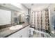 Clean bathroom boasts granite countertop, white cabinets, and a patterned shower curtain at 39822 Harmon Grove Ct, Zephyrhills, FL 33540
