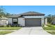 Single-story home with gray garage door and landscaped front yard at 39822 Harmon Grove Ct, Zephyrhills, FL 33540