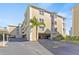 Inviting exterior view of a tan multi-story condo building featuring convenient covered parking and lush landscaping at 399 150Th Ave # A203, Madeira Beach, FL 33708