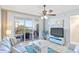 Bright living room featuring a ceiling fan and sliding glass doors to a balcony with views of the water at 399 150Th Ave # A203, Madeira Beach, FL 33708