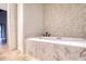 Spa-like bathroom with a soaking tub and pebble tile accent wall at 1312 Pasadena S Ave # 14, South Pasadena, FL 33707