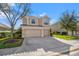 Two-story house with beige exterior, two-car garage, and lush landscaping at 2215 Clarine N Way, Dunedin, FL 34698