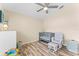 Bright bedroom with ceiling fan, wood-look floors, crib, and rocking chair with ottoman at 24034 Geese Cir, Land O Lakes, FL 34639