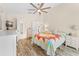 Bright bedroom features wood flooring, a ceiling fan, TV, dresser and colorful quilt on the bed at 24034 Geese Cir, Land O Lakes, FL 34639