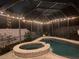 A relaxing screened pool with a built-in spa, illuminated by string lights for evening enjoyment at 24034 Geese Cir, Land O Lakes, FL 34639