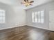 Spacious bedroom with wood floors, two windows with shutters, and ceiling fan at 10130 Balcony St, New Port Richey, FL 34655