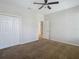 Well-lit bedroom with carpet, ceiling fan and access to another room at 10130 Balcony St, New Port Richey, FL 34655