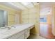 Bathroom vanity with a white countertop and an expansive mirror reflecting an adjacent living space with hardwood floors at 1808 Cypress Trace Dr # 1808, Safety Harbor, FL 34695