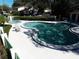 Inviting community pool with lush landscaping, lounge chairs, and a tranquil hot tub in a serene setting at 1808 Cypress Trace Dr # 1808, Safety Harbor, FL 34695