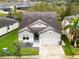 Aerial view of a two-story house with gray siding, a three-car garage, and landscaping at 7465 Yale Harbor Dr, Wesley Chapel, FL 33545