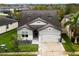 Aerial view of a two-story house with gray siding, a three-car garage, and landscaping at 7465 Yale Harbor Dr, Wesley Chapel, FL 33545