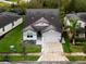 Aerial view of a two-story house with gray siding, a three-car garage, and landscaping at 7465 Yale Harbor Dr, Wesley Chapel, FL 33545