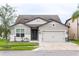 Two-story house with gray siding, two-car garage, and landscaping at 7465 Yale Harbor Dr, Wesley Chapel, FL 33545