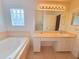 Bathroom featuring a soaking tub, a neutral vanity, tile flooring, and a window for natural light at 10232 Oakhurst Rd, Largo, FL 33774