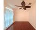 A bright, empty bedroom showcases hardwood floors, neutral walls, and a unique leaf-design ceiling fan at 10232 Oakhurst Rd, Largo, FL 33774