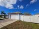 Attached garage with a white door on a blue single-story house with a concrete driveway and a white fence at 10232 Oakhurst Rd, Largo, FL 33774