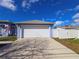 Front view of a blue home's two-car garage with a white door and an extended driveway on a sunny day at 10232 Oakhurst Rd, Largo, FL 33774