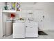 Washer and dryer setup with overhead shelving, providing an efficient laundry area at 1050 Starkey Rd # 704, Largo, FL 33771