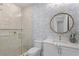 Charming bathroom with a glass shower, patterned wallpaper, and a stylish vanity with a round mirror at 6189 Leeland S St, St Petersburg, FL 33715