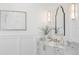Elegant bathroom featuring marble countertops, wainscoting, decorative mirror, and stylish sconces at 6189 Leeland S St, St Petersburg, FL 33715