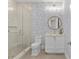 Charming bathroom with a glass shower, patterned wallpaper, and a stylish vanity with a round mirror at 6189 Leeland S St, St Petersburg, FL 33715