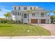 Stunning multi-story white home with lush landscaping, brick driveway, and attached garages, blending luxury and curb appeal at 6189 Leeland S St, St Petersburg, FL 33715