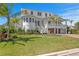 Beautiful home featuring pristine white exterior, lush green lawn, mature palm trees, and manicured landscaping at 6189 Leeland S St, St Petersburg, FL 33715