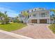 Elegant white home with lush landscaping, complemented by a brick driveway leading to attached garages at 6189 Leeland S St, St Petersburg, FL 33715