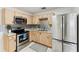 Well-lit kitchen with modern stainless steel appliances, light wood cabinetry, and decorative backsplash, creating a functional space at 3918 W Fig St, Tampa, FL 33609