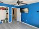 Bright bedroom with blue walls, laminate flooring, and a large TV at 8003 Bally Money Rd, Tampa, FL 33610