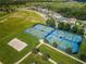Aerial view of community tennis courts, volleyball court, and sports field amid green landscaping and residential homes at 8319 Swiss Chard Cir, Land O Lakes, FL 34637