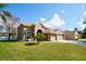 Two-story house with tan exterior, three-car garage, and manicured lawn at 2012 Fern Ridge Ct, Holiday, FL 34691