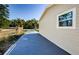 A long driveway stretches along a modern home exterior, complemented by lush greenery and clear blue skies at 3562 Fisher Rd, Palm Harbor, FL 34683