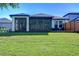 Back exterior view of the house showing a large screened porch and grassy yard at 4956 Rolling Green Dr, Wesley Chapel, FL 33543