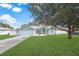 Light teal house with a white fence, landscaping, and a large tree in the front yard at 5112 Teather St, Spring Hill, FL 34608