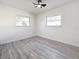 Bedroom with two windows, ceiling fan, and grey wood-look floors at 5128 49Th N Ave, St Petersburg, FL 33709