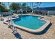 Freeform community pool with a chair lift, lounge chairs, umbrellas, and a covered area at 122 E Cypress Ct # 22, Oldsmar, FL 34677
