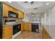 Kitchen with tile floors, black appliances, wood cabinets and a view into the living area at 122 E Cypress Ct # 22, Oldsmar, FL 34677