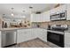 Modern kitchen featuring white cabinets, granite counters, and stainless steel appliances at 19029 Us Highway 19 N # 13F, Clearwater, FL 33764