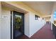 Apartment 403 entrance with glass storm door and a view of the treeline and red balcony in the reflection at 9433 Harbor Greens Way # 403, Seminole, FL 33776